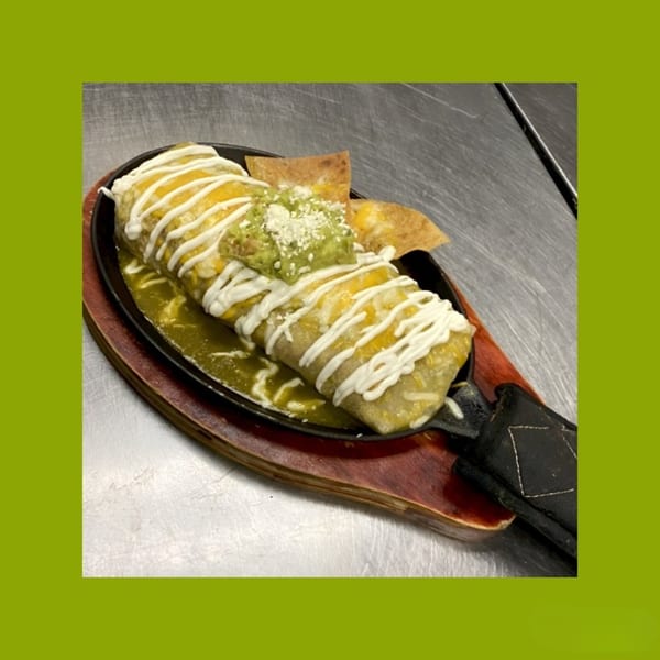 A sizzling La Familia Callejas Mexican Food burrito covered in cheese, sour cream, and guacamole.